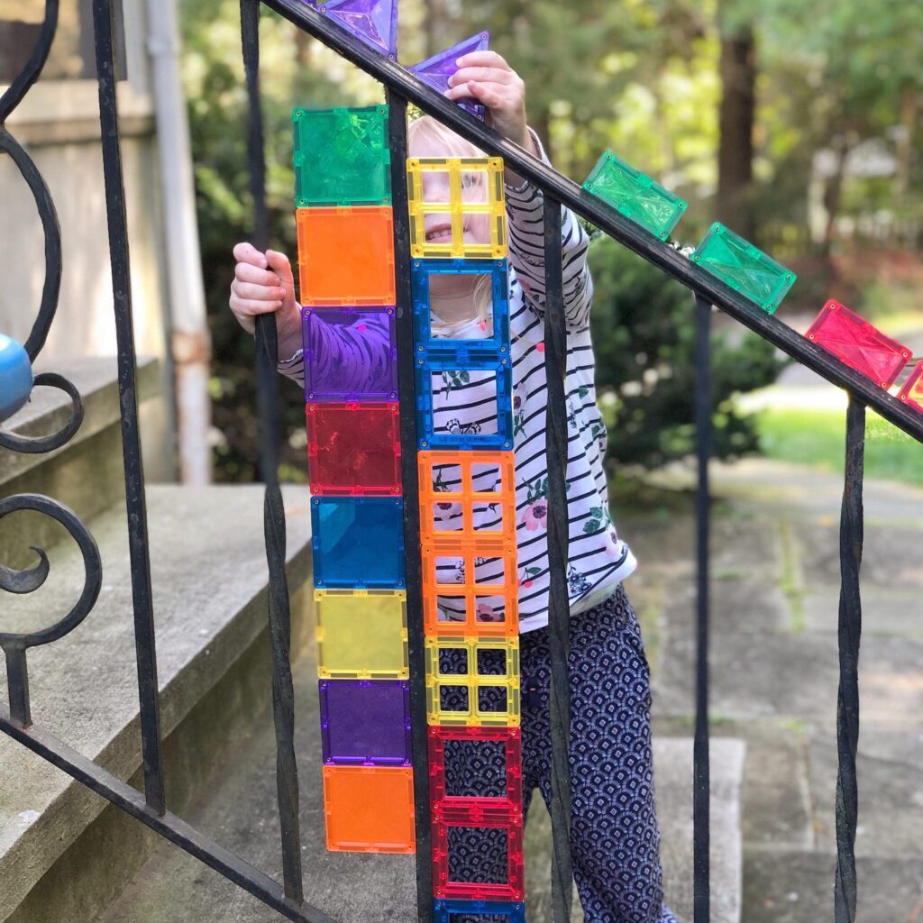 Child playing with Connetix Tiles attached to metal railing