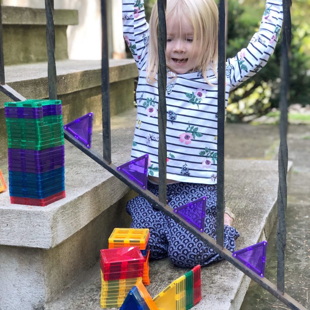Child playing with Connetix Tiles attached to metal railing